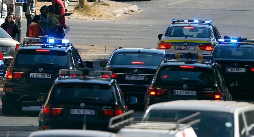 Convoy of official vehocles with flashing blue lights