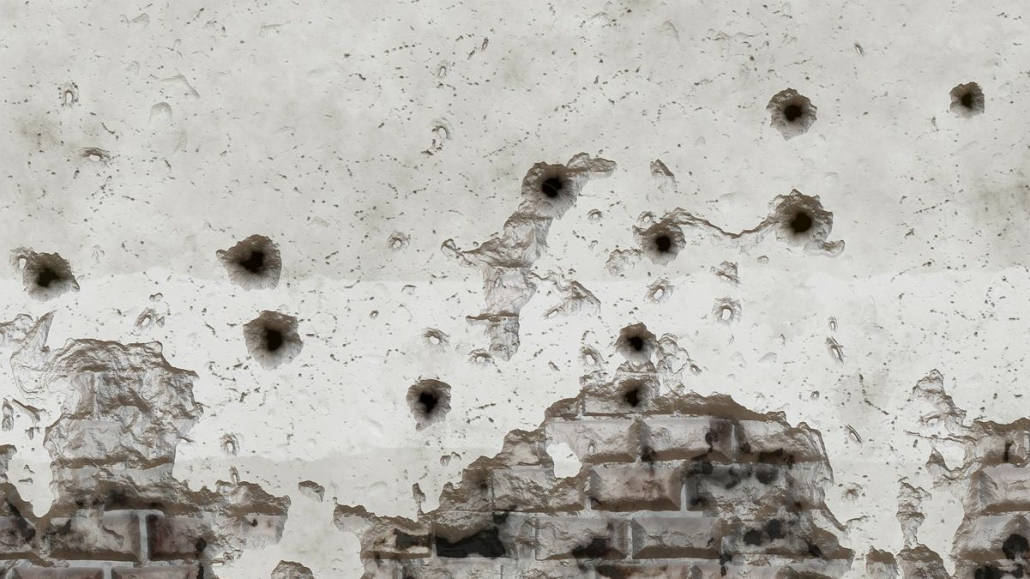 A wall marked with bullet holes