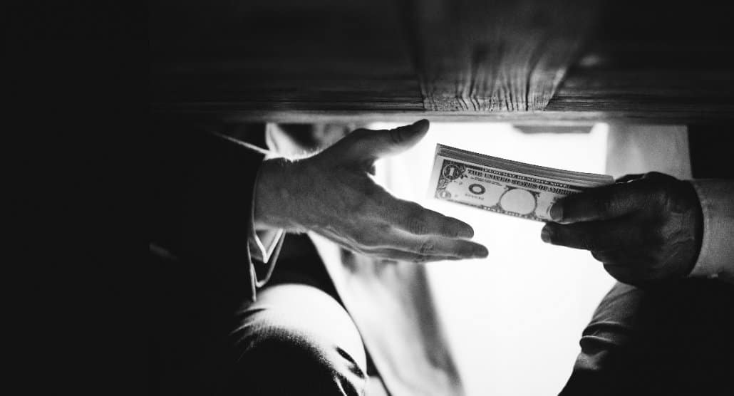 Photo of hands passing money under the table