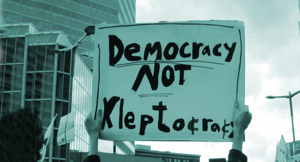 Protest placard reading "democracy not kleptocracy".