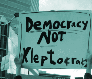 Protest placard reading "democracy not kleptocracy".