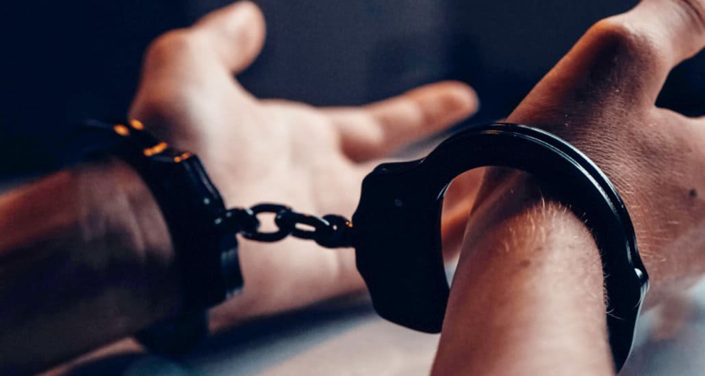 Close-up photo of handcuffs on a person's wrists